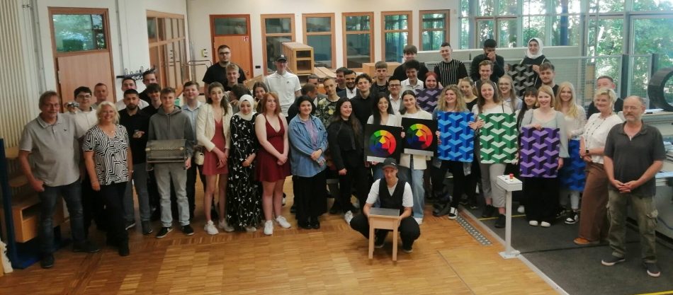Teilnehmer und pädagogisch Verantwortliche des Projekts „Chancen geben – Chancen nutzen: Fit für die Ausbildung“ der Osthushenrich-Stiftung aus dem letzten Schuljahr zeigen im Holzzentrum des Reckenberg-Berufskollegs einige Arbeiten.